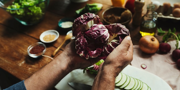 Manos sostienen un vegetal en una cocina.