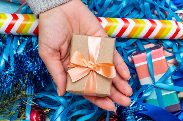 Manos en un suéter de punto con caja de regalo. Concepto de preparación de vacaciones de Navidad.