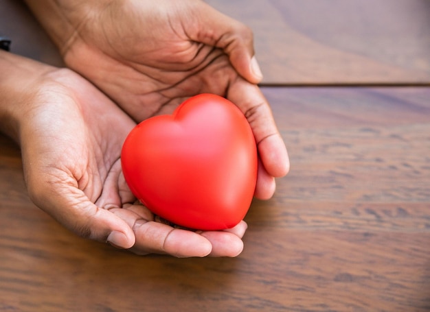 Manos sujetando un corazón rojo