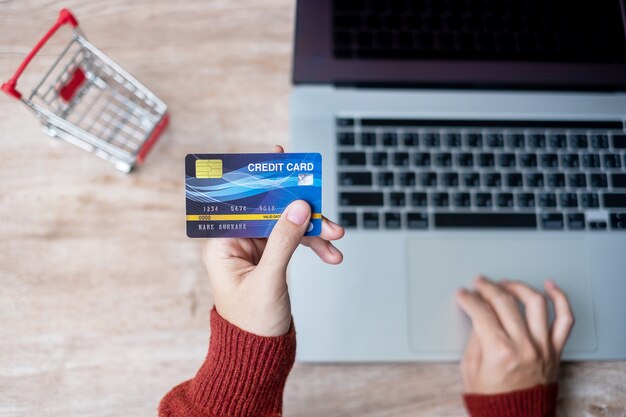 Manos con tarjeta de crédito y computadora portátil para compras en línea