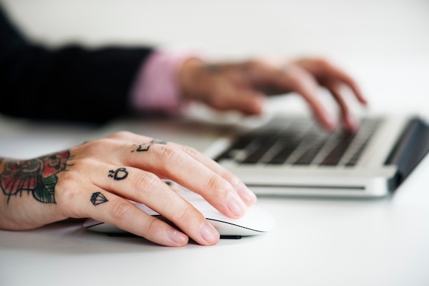 Manos con tatuaje escribiendo en un teclado