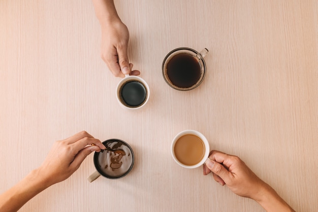 Manos con tazas de café en la superficie de madera