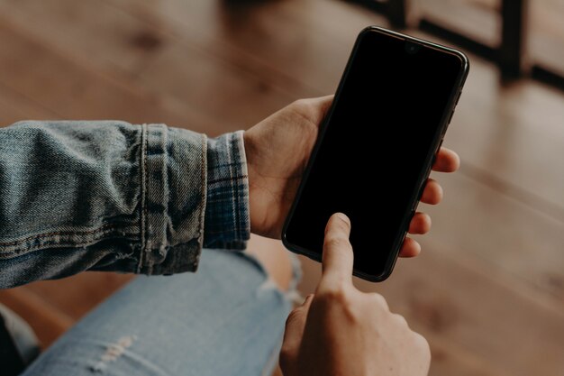 Manos con un teléfono negro. teléfono inteligente