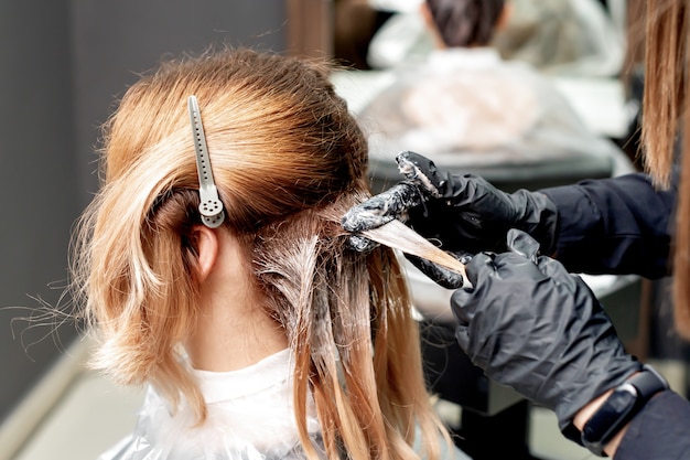 Manos teñiendo el cabello de mujer