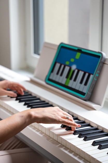 Las manos tocando un teclado mientras se sigue una aplicación de aprendizaje interactivo en una tecnología de tableta permite