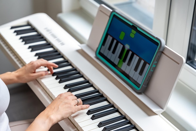 Las manos tocando un teclado mientras se sigue una aplicación de aprendizaje interactivo en una tecnología de tableta permite