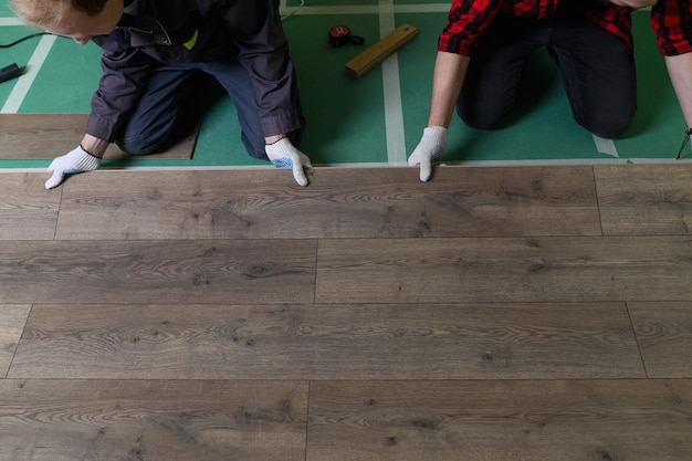 Manos de un trabajador golpeando un laminado que conecta los paneles con un clic de bloqueo