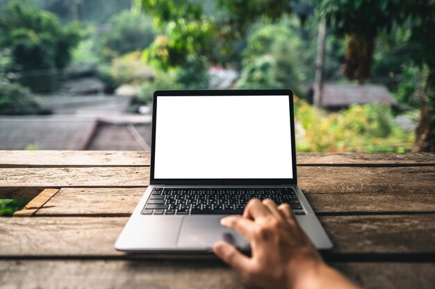 Manos trabajando en una computadora portátil en el balcón de una casa de campo