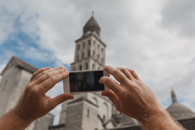Manos de turista sosteniendo teléfonos inteligentes tomando fotos de Perigueux, Francia