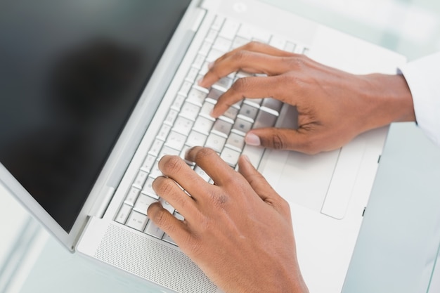 Manos usando la computadora portátil en la oficina médica