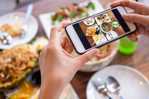 Foto manos usando un teléfono para tomar fotos de comida