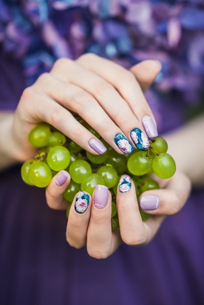 Foto manos con uñas con uvas