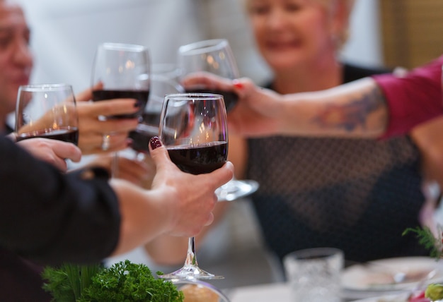 Manos con vasos de vino tinto de cerca.