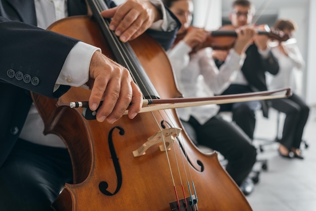 Las manos del violonchelista profesional se cierran y está actuando con la sección de cuerdas de la orquesta sinfónica.