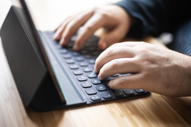 Mans Hände arbeiten auf dem Tablet zu Hause Telearbeit