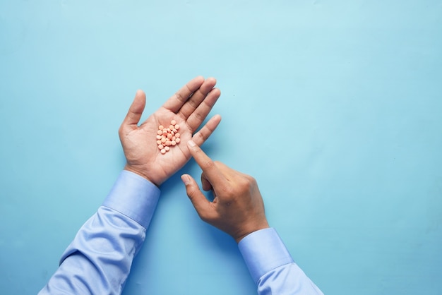 Mans Hand mit Medizin aus dem Tablettenbehälter verschüttet