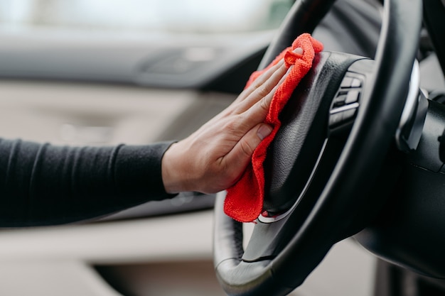 Mans Handreinigung Luxusauto Interieur. Lenkrad während Coronavirus abwischen. Auto automatisch von innen waschen. Hygienekonzept