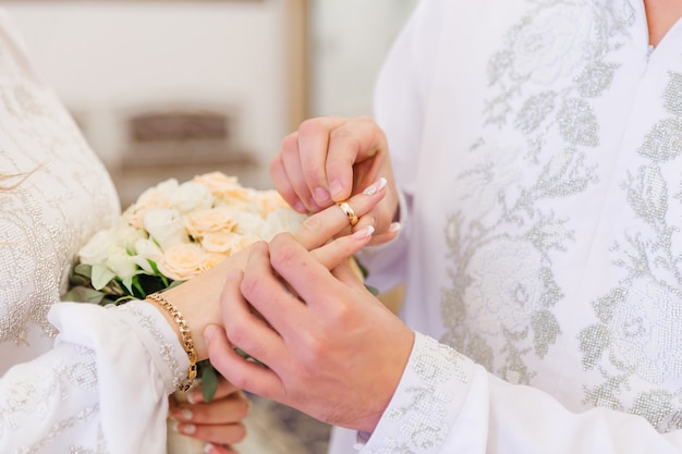 Mans mano poniendo un anillo de bodas en el dedo de una mujer