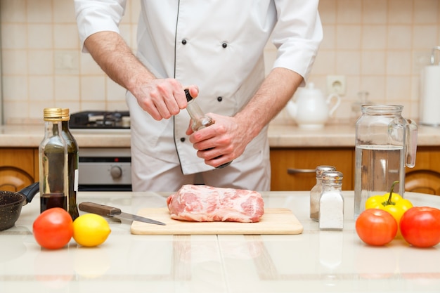 Mans mano sostiene una botella con souce cocinero profesional preparar la carne