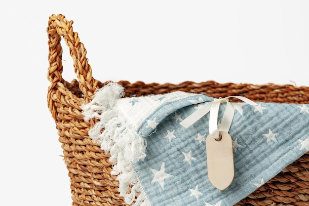 Manta de algodón suave en una cesta de paja sobre fondo blanco.