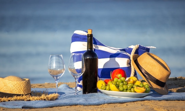 Manta de piquenique, vinho, frutas, linda praia de mar. Foco seletivo