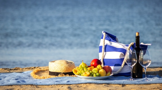 Manta de picnic, vino, fruta, hermosa playa de mar. Enfoque selectivo
