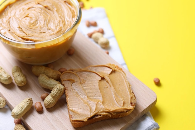 Foto manteiga de amendoim e manteiga de amendoim espalhadas em uma tábua com uma tigela de manteiga de amendoim e manteiga de amendoim.
