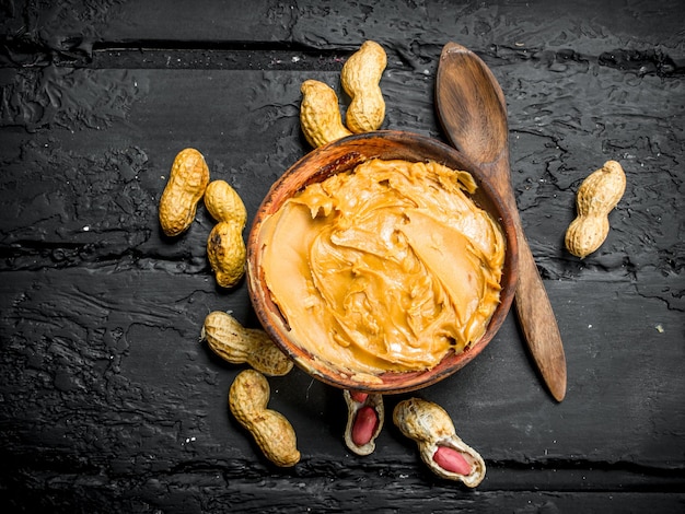 Foto manteiga de amendoim em tigela com colher de pau