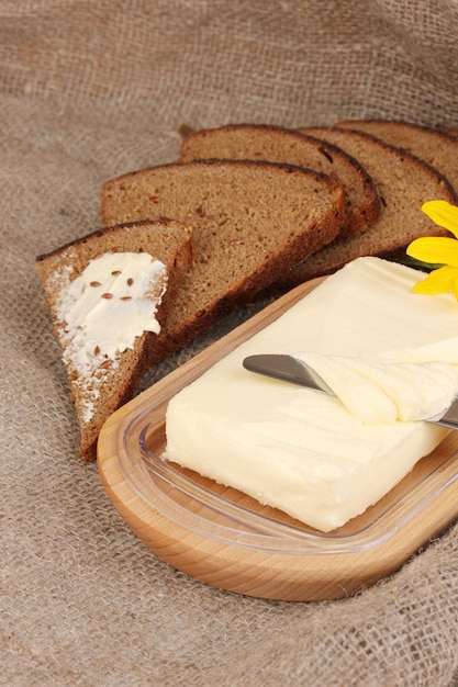 manteiga em suporte de madeira cercada por pão e flores em fundo de saco