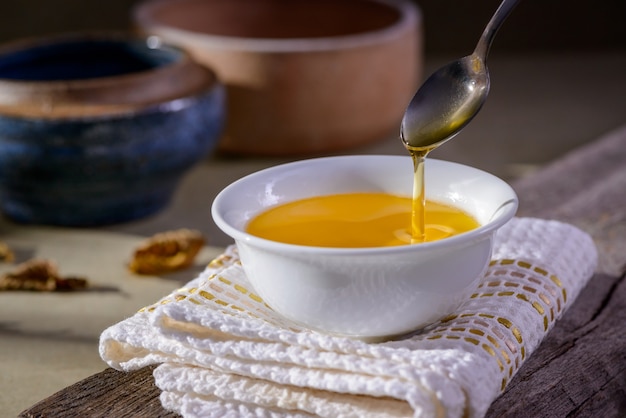 Manteiga ghee da Índia em um recipiente de talheres branco na mesa de madeira.