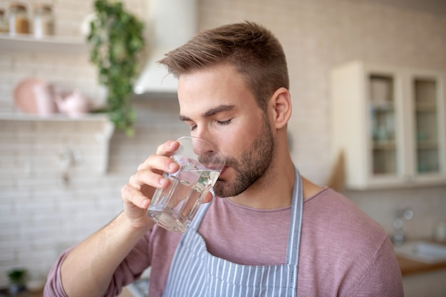 Mantener el equilibrio hídrico. Un joven barbudo bebiendo agua limpia.