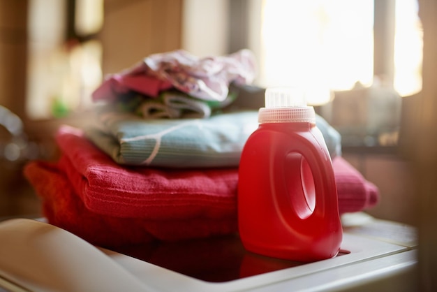 Mantener limpia la ropa Toma de una botella de detergente y una pila de ropa encima de una lavadora