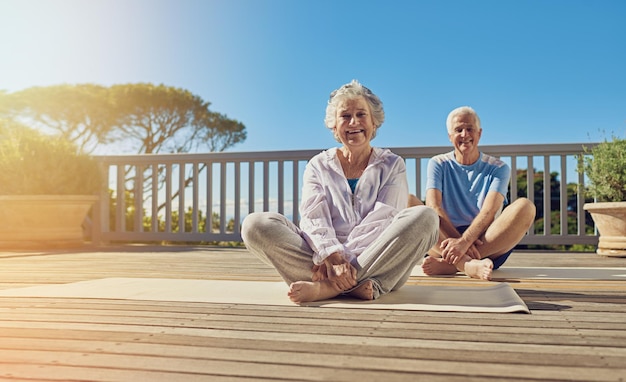 Mantener una mente y un cuerpo sanos Foto de una pareja mayor haciendo yoga juntos en su patio exterior