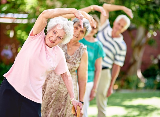 Mantenerse activo es clave para una jubilación saludable Foto de un grupo de ancianos sonrientes haciendo ejercicio al aire libre