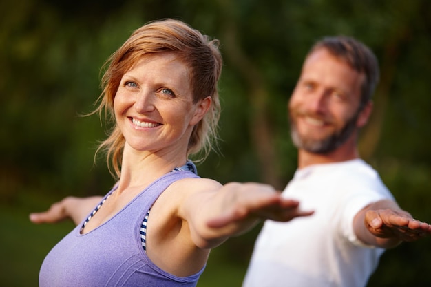 Mantenerse en buena forma Foto de una mujer atractiva haciendo yoga con su pareja al aire libre