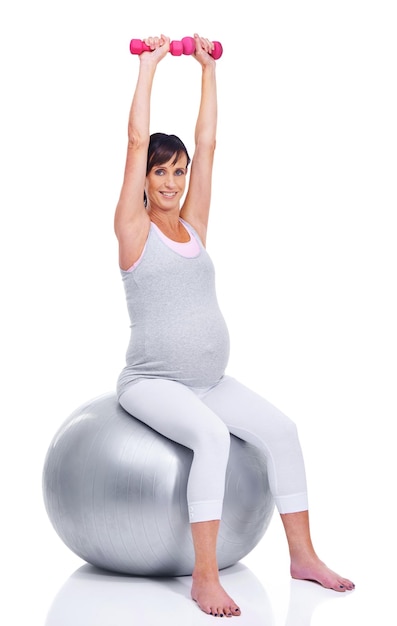 Mantenerse en forma hasta su último trimestre Una madre embarazada sonriendo con una pelota de pilates mientras está aislada en blanco