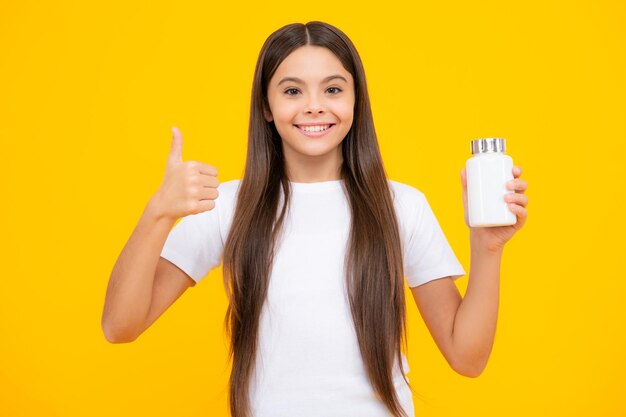 Mantenerse saludable Adolescente sosteniendo píldoras de vitaminas sobre fondo amarillo aislado Retrato de adolescente feliz Chica sonriente