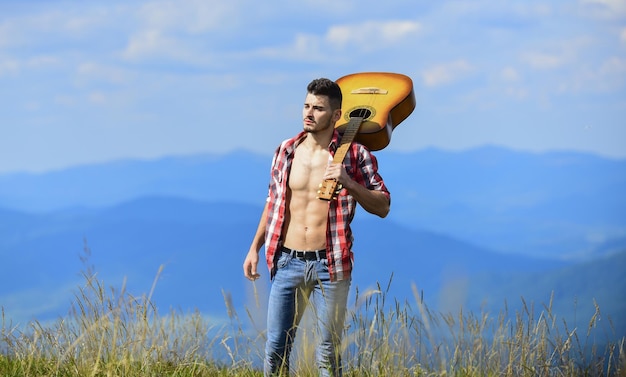 Mantenga la calma y escuche. hombre sexy con guitarra en camisa a cuadros. moda hipster. camping occidental. feliz y libre. hombre de vaquero con torso musculoso desnudo. guitarrista acústico. Canción de música country.