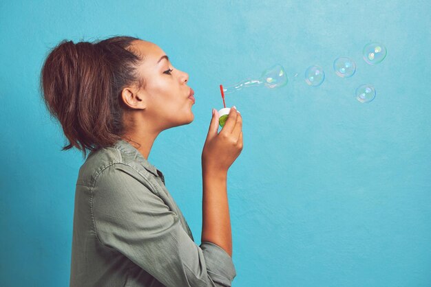 Mantenga la calma y haga burbujas Captura recortada de una mujer joven que hace burbujas contra un fondo azul