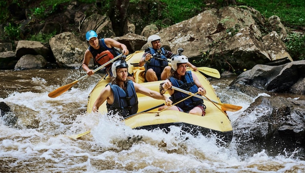 Manténganla estable, muchachos Foto de un grupo de jóvenes decididos en un bote de goma ocupados remando en fuertes rápidos de río afuera durante el día