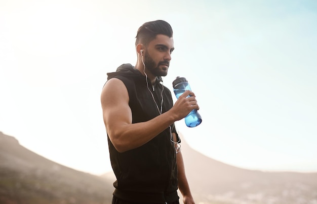 Manténgase hidratado para optimizar su entrenamiento Foto de un joven deportivo bebiendo agua mientras hace ejercicio al aire libre