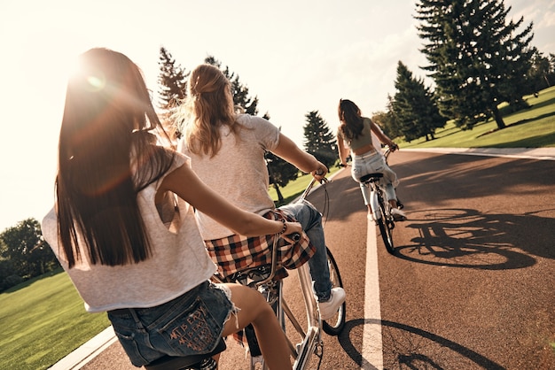 Mantenha a calma e continue andando. Retrovisor de jovens em trajes casuais andando de bicicleta juntos enquanto passam tempo despreocupados ao ar livre