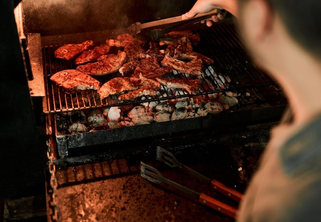 Mantenha a calma e grelhe na captura de um homem irreconhecível grelhando carne enquanto faz um churrasco