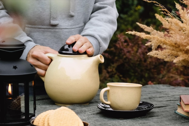 Mantenha a festa do chá quente de outono Mãos femininas derramando chá na caneca bebendo chá ao ar livre