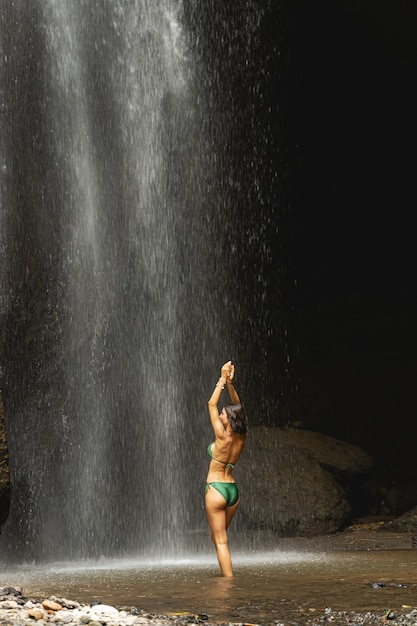 Foto mantenha-se em forma. mulher atraente em pé na água e curtindo a cachoeira, conceito de turismo