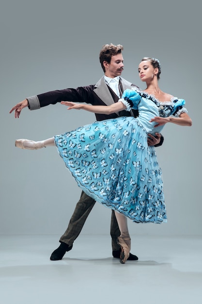 Manteniendo una dirección. Hermosos bailarines de salón de baile contemporáneos aislados sobre fondo gris de estudio. Artistas profesionales sensuales bailando walz, tango, slowfox y quickstep. Flexible y ingrávido.