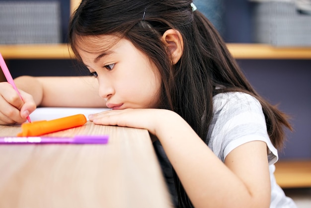 Manteniéndose ocupado. Foto de una niña escribiendo en casa.