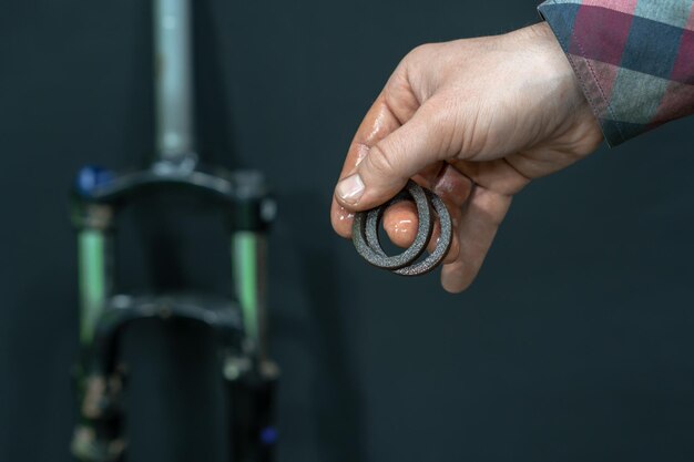 Mantenimiento de un aceite de horquilla amortiguador moderno y reemplazo de sellos de aceite Reparación de bicicletas de montaña en un taller profesional Partes de la horquilla en la mano del mecánico sobre un fondo negro