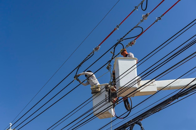 El mantenimiento de los electricistas trabaja con electricidad de alto voltaje en el cucharón hidráulico.