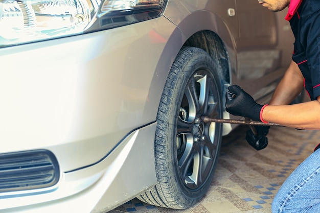 Mantenimiento y servicio del cuidado del automóvil Mecánico de automóviles del técnico de la mano del primer plano que utiliza el concepto de reparación y reparación del neumático de cambio de llave y el soporte del servicio de seguro y el problema del automóvil